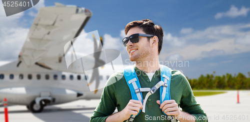 Image of smiling man with backpack over plane on airfield