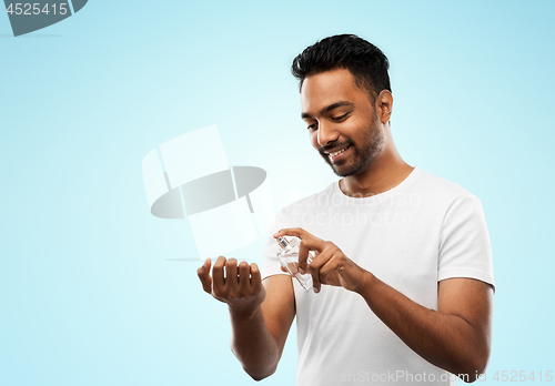 Image of happy indian man with perfume over blue background