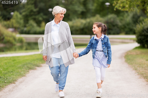 Image of grandmother and granddaughter walking at park