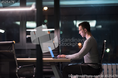 Image of man working on laptop in dark office