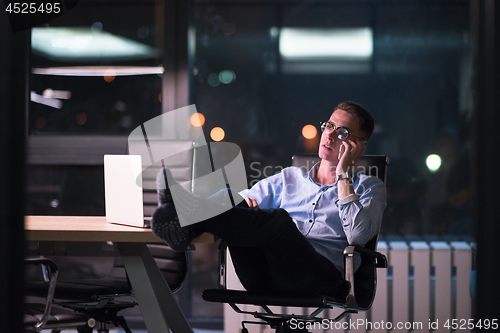 Image of businessman using mobile phone in dark office