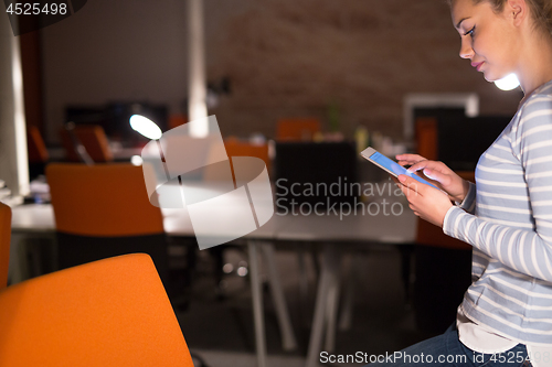 Image of woman working on digital tablet in night office