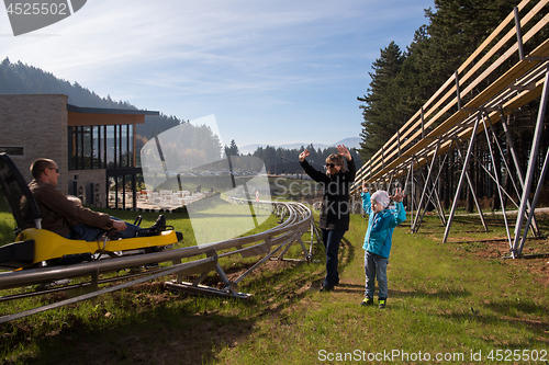 Image of Happy family driving on alpine coaster