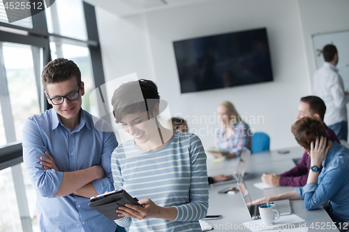 Image of Two Business People Working With Tablet in office