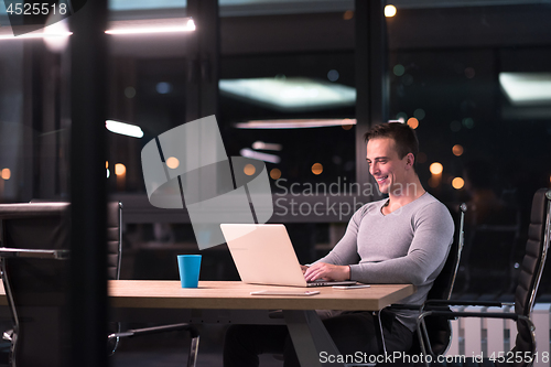 Image of man working on laptop in dark office