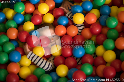 Image of boy having fun in hundreds of colorful plastic balls