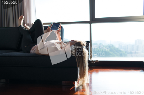 Image of Lovely Blond Woman Listening To Music while resting on couch