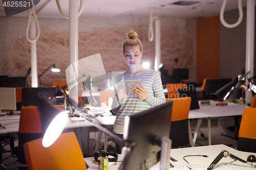 Image of woman working on digital tablet in night office