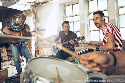 Image of Repetition of rock music band. Electric guitar player and drummer behind the drum set.