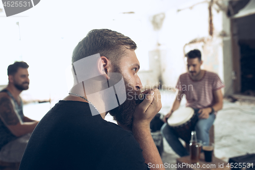 Image of Repetition of rock music band. man with harmonica and drummer behind the drum set.