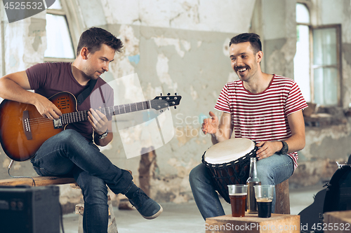 Image of Repetition of rock music band. Electric guitar player and drummer behind the drum set.