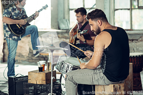 Image of Repetition of rock music band. Electric guitar player and drummer behind the drum set.