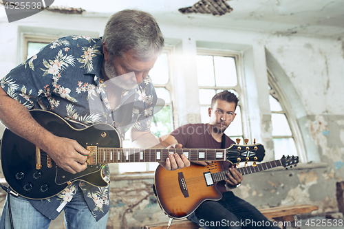 Image of Repetition of rock music band. Electric guitar player and drummer behind the drum set.