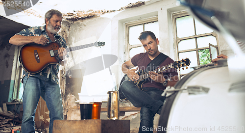 Image of Repetition of rock music band. Electric guitar player and drummer behind the drum set.