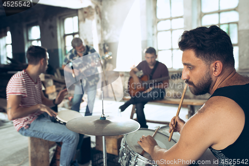 Image of Repetition of rock music band. Electric guitar player and drummer behind the drum set.