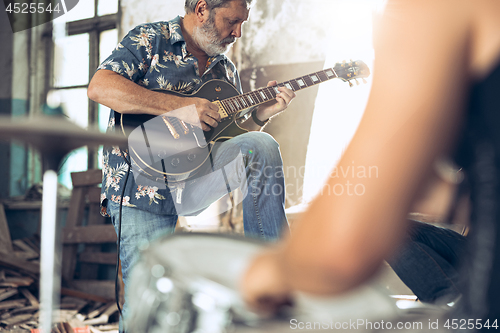 Image of Repetition of rock music band. Electric guitar player and drummer behind the drum set.