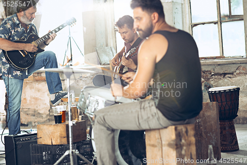 Image of Repetition of rock music band. Electric guitar player and drummer behind the drum set.