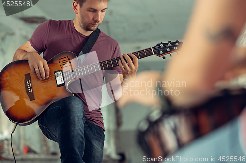 Image of Repetition of rock music band. Electric guitar player and drummer behind the drum set.