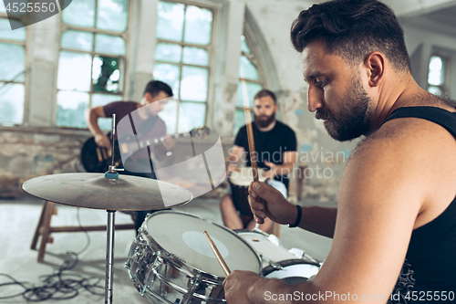 Image of Repetition of rock music band. Electric guitar player and drummer behind the drum set.