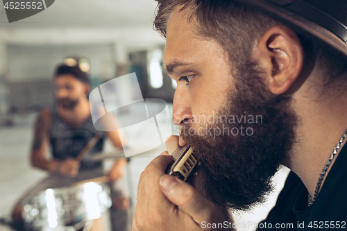 Image of Repetition of rock music band. man with harmonica and drummer behind the drum set.