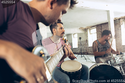 Image of Repetition of rock music band. Electric guitar player and drummer behind the drum set.