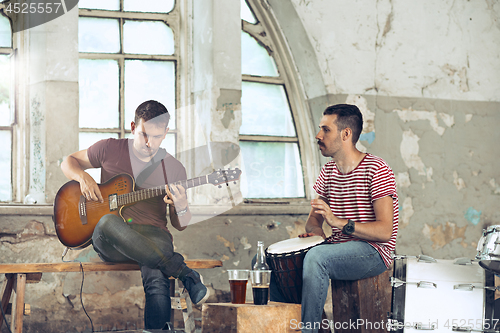 Image of Repetition of rock music band. Electric guitar player and drummer behind the drum set.