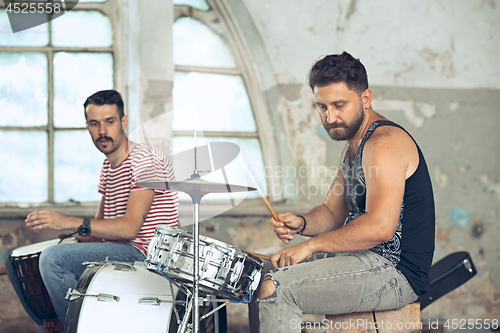 Image of Repetition of rock music band. Electric guitar player and drummer behind the drum set.