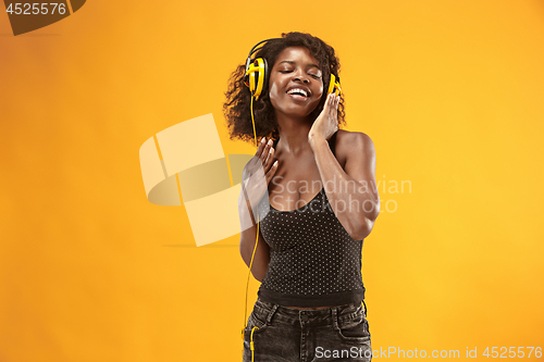 Image of Studio portrait of adorable curly girl happy smiling during photoshoot. Stunning african woman with light-brown skin relaxing in headphones