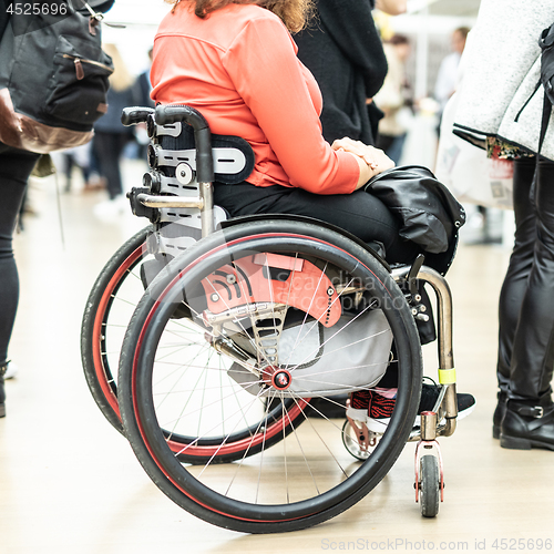 Image of Close up of unrecognizable hanicapped woman on a wheelchair queuing in line to perform everyday tasks.