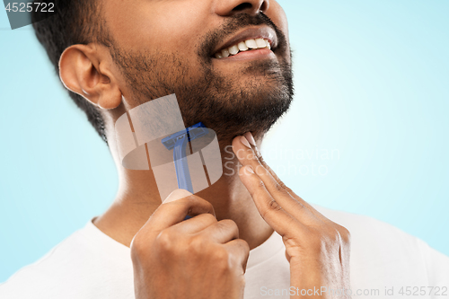 Image of close up of man shaving beard with razor blade