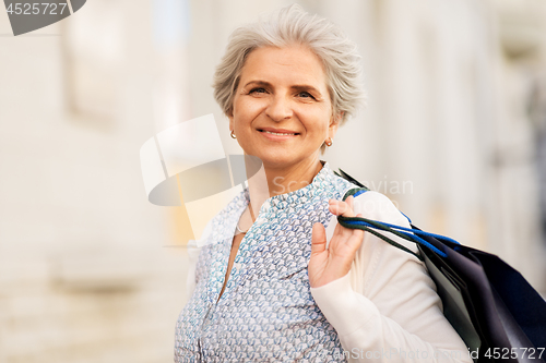 Image of senior woman with shopping bags on city street