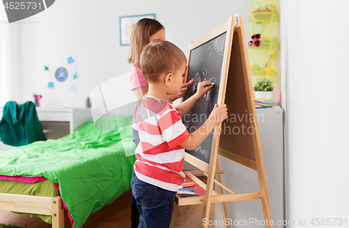 Image of happy kids drawing on chalk board at home