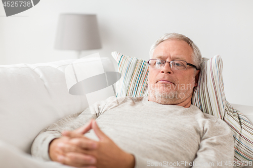 Image of senior man  lying on sofa and thinking at home