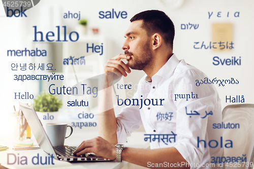 Image of man with laptop over words in foreign languages