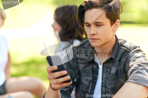 Image of man using smartphone with friends at summer park