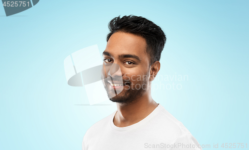 Image of smiling young indian man over blue background