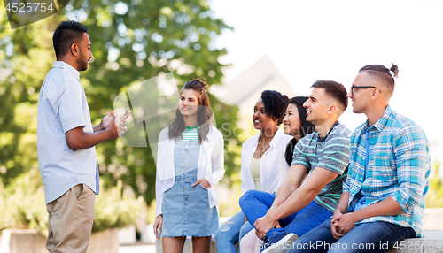 Image of happy international friends talking in park