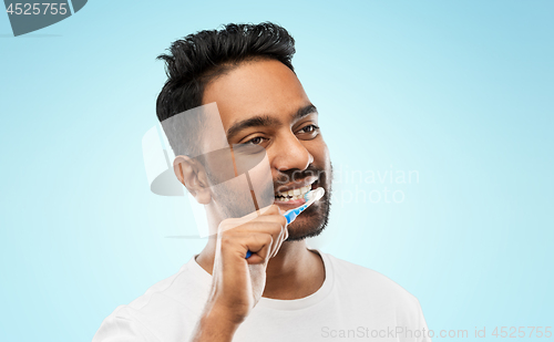 Image of indian man with toothbrush cleaning teeth