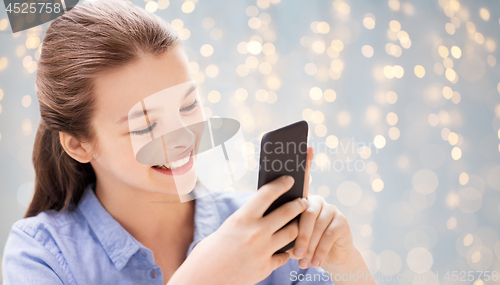 Image of girl messaging on smartphone over festive lights