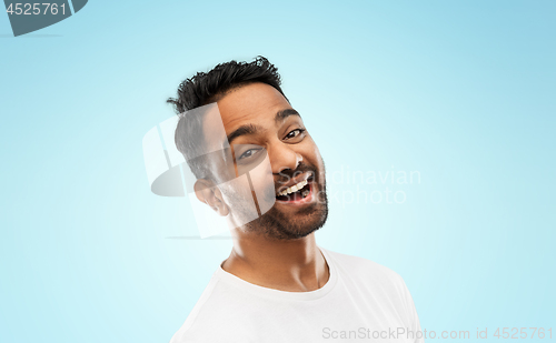 Image of young laughing indian man over blue background