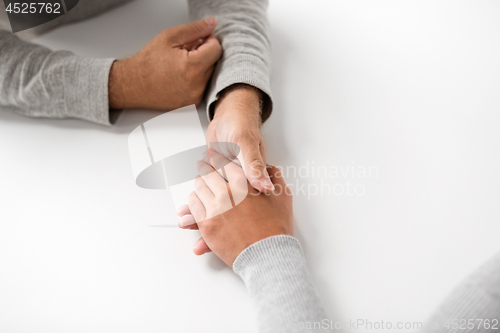 Image of close up of young woman holding senior man hands