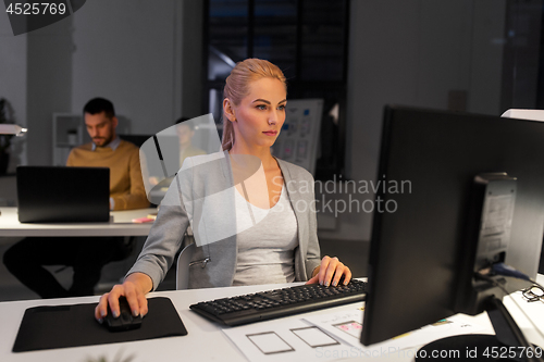Image of designer working on computer at night office
