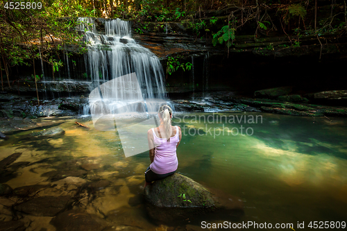 Image of Woman enjoying nature. Dappled sunlight at the waterfall rock pool