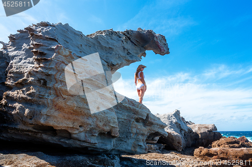 Image of Woman standing in a sandstone formation by the ocean