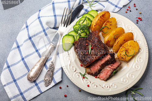 Image of Steak with pink pepper, rosemary and baked potatoes.