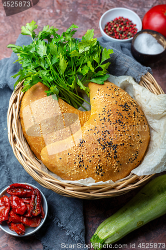 Image of Pizza calzone with zucchini, dried tomatoes and cheese.