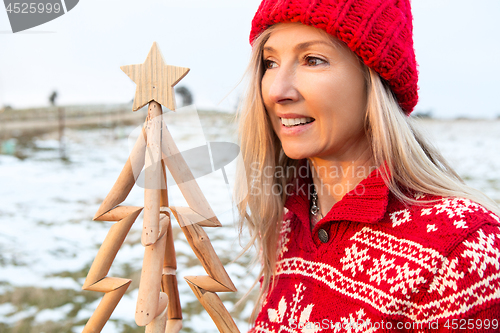 Image of Woman holding a timber Christmas Tree, Christmas season, Christmas in July themes