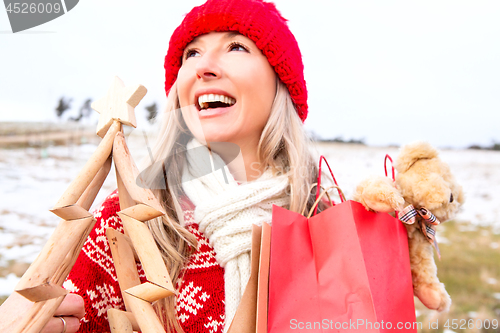 Image of Joyous woman holding small wooden Christmas tree and gift bags