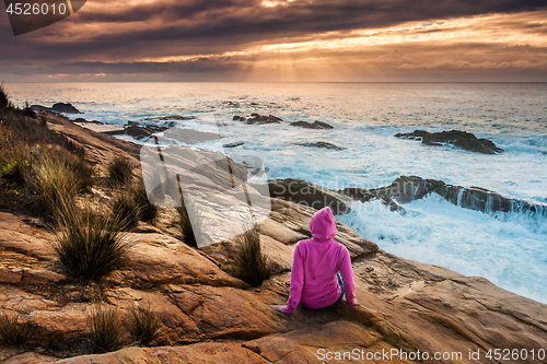 Image of Woman enjoys views of sunbeams and sea flows