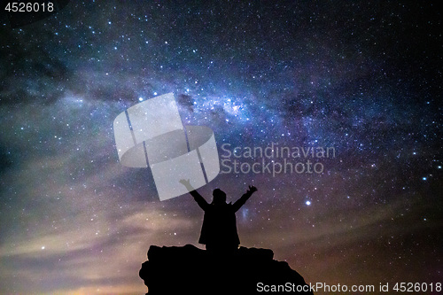 Image of Silhouetted person hails the cosmos milky way starry night sky